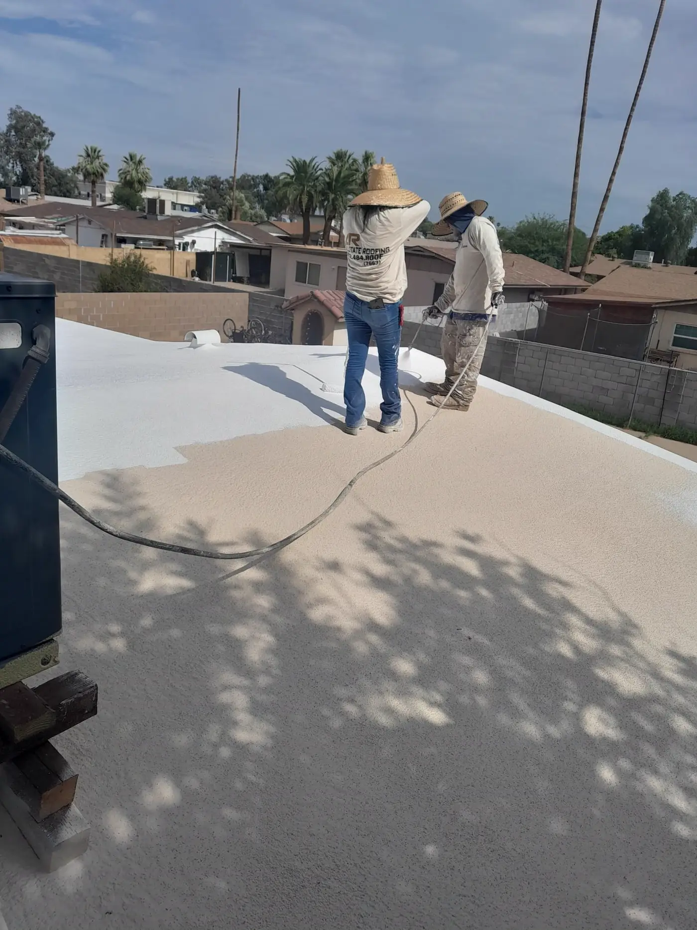 Allstate Roofing crew applying elastomeric coating to a flat roof in Arizona